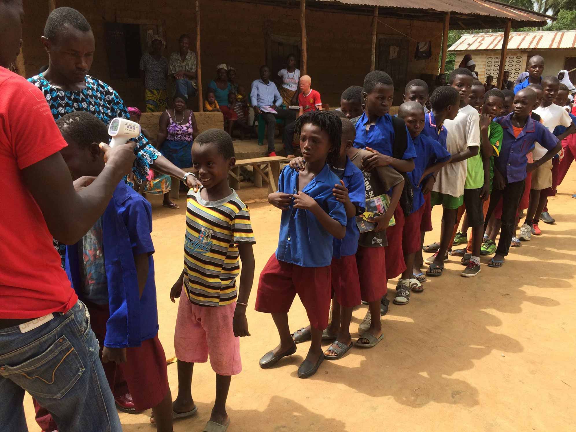 In Sierra Leone, uno degli "health promoter" di EMERGENCY misura la febbre ai bambini di un villaggio